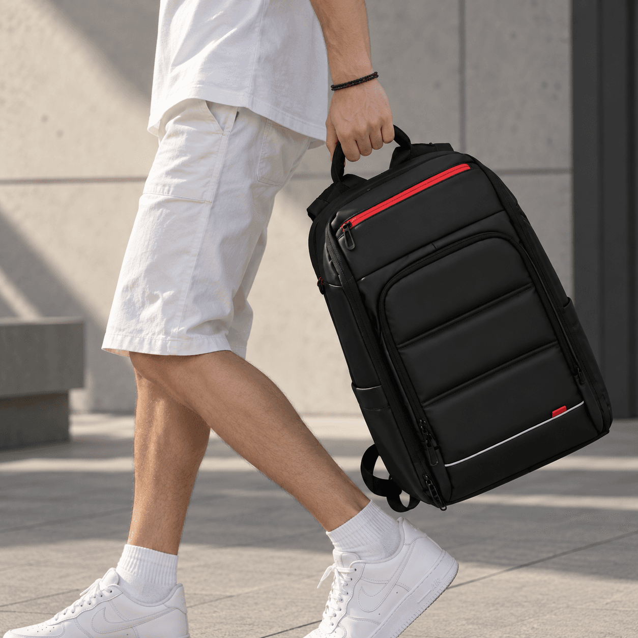 Mann trägt den Laptop-Rucksack am Griff durch die Stadt